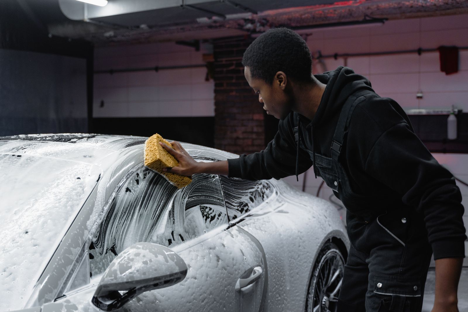 Detailer washing a car with a sponge and foam